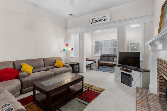 carpeted living room featuring ceiling fan and a brick fireplace