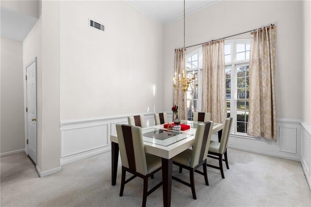 dining space featuring ornamental molding, a chandelier, and light colored carpet