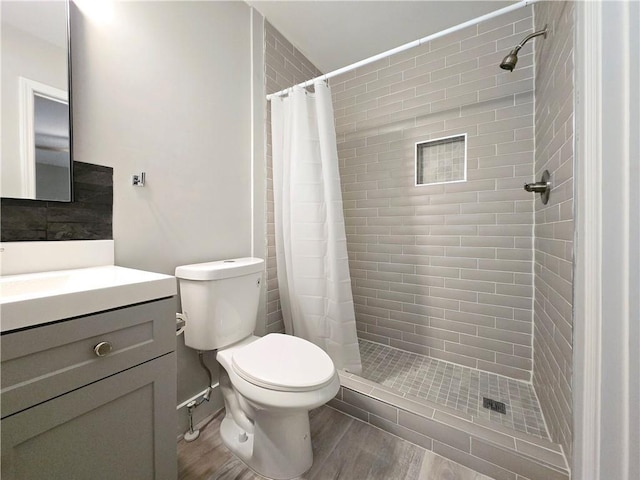 bathroom featuring vanity, hardwood / wood-style flooring, toilet, and walk in shower