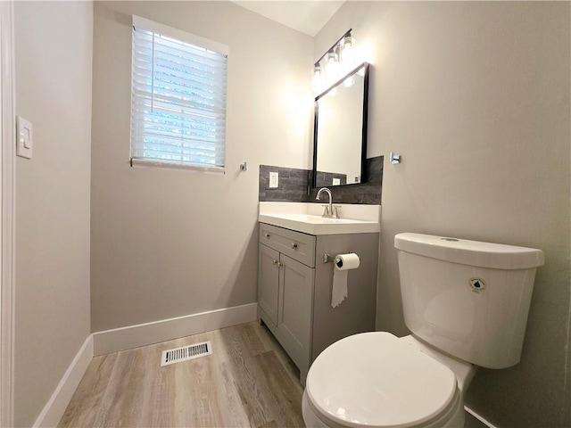 bathroom featuring vanity, hardwood / wood-style floors, tasteful backsplash, and toilet