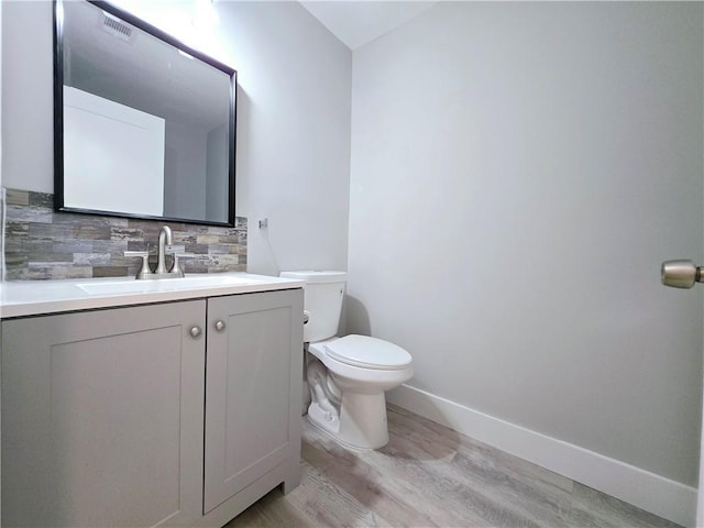 bathroom with vanity, toilet, hardwood / wood-style floors, and backsplash