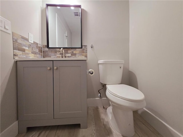 bathroom with vanity, hardwood / wood-style floors, tasteful backsplash, and toilet