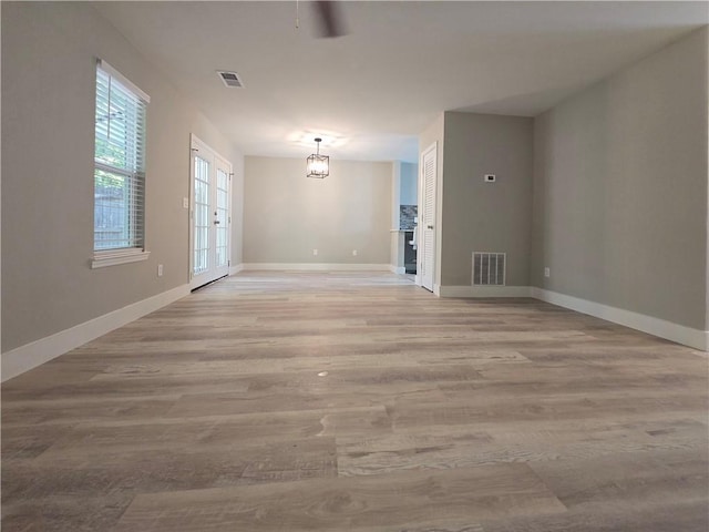 unfurnished room with a notable chandelier and light hardwood / wood-style flooring