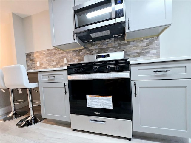 kitchen with appliances with stainless steel finishes, white cabinets, and backsplash