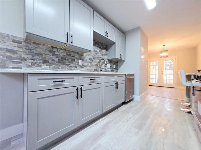 kitchen with decorative light fixtures, tasteful backsplash, sink, stainless steel dishwasher, and french doors