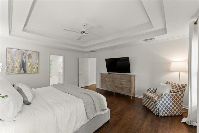 bedroom with a tray ceiling, visible vents, ornamental molding, and wood finished floors