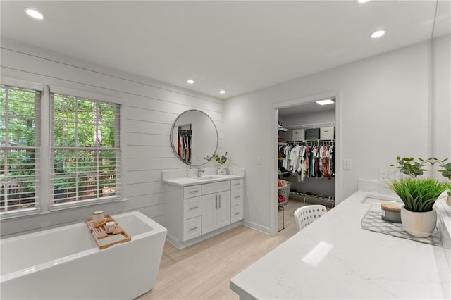 bathroom featuring vanity, recessed lighting, a freestanding tub, and wood finished floors