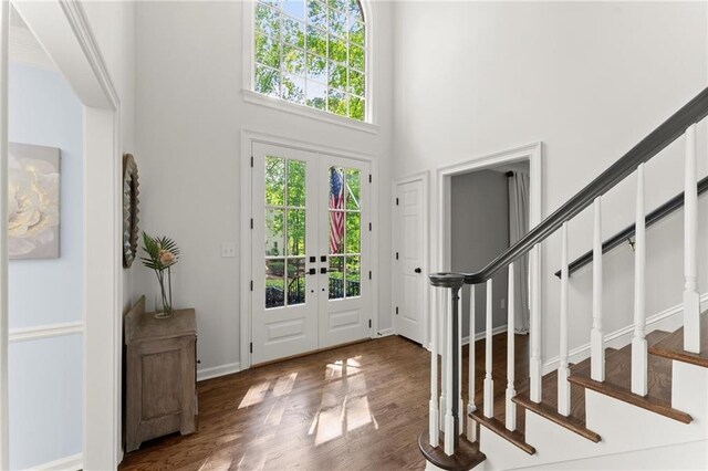entryway featuring wood finished floors, french doors, stairway, and a towering ceiling