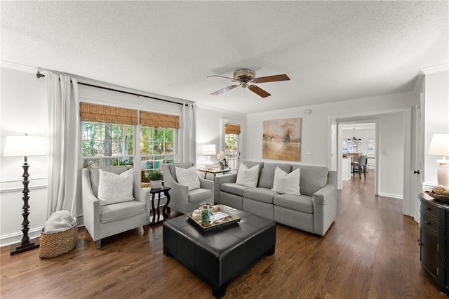 living room featuring a textured ceiling, ornamental molding, dark wood-style flooring, and ceiling fan
