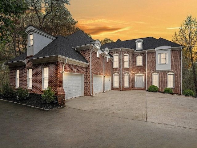 view of front of house with brick siding, a garage, driveway, and roof with shingles