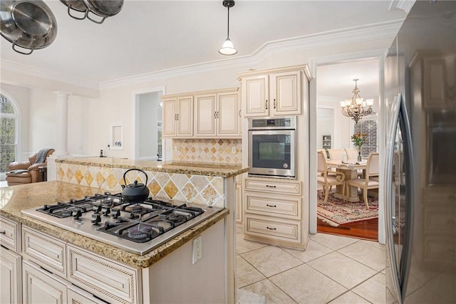 kitchen featuring ornamental molding, a chandelier, light tile patterned floors, cream cabinets, and appliances with stainless steel finishes