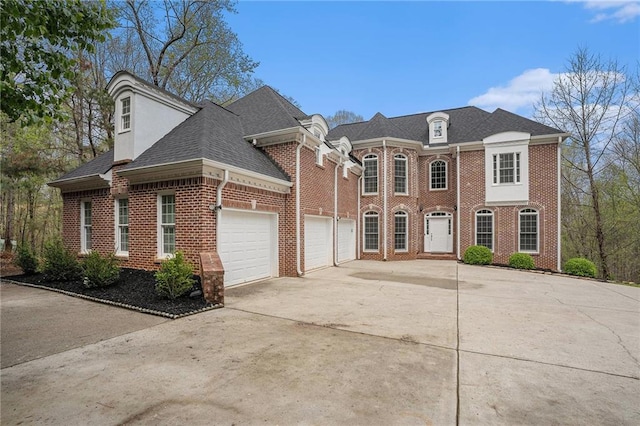 view of front facade with a shingled roof, driveway, a garage, and brick siding