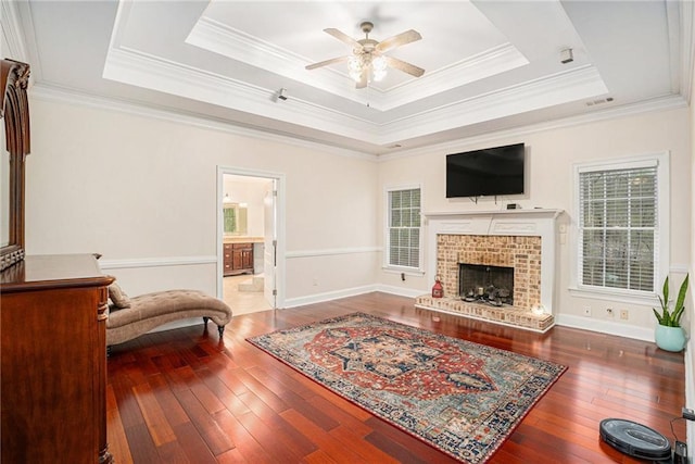 living room featuring a raised ceiling, ceiling fan, wood-type flooring, and ornamental molding
