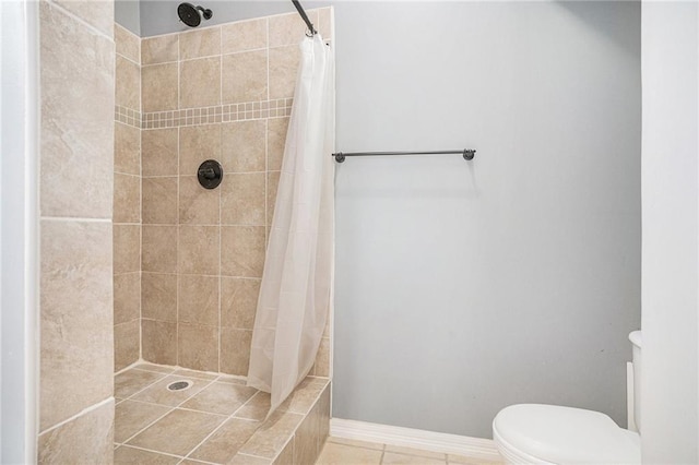full bath featuring tile patterned floors, tiled shower, baseboards, and toilet