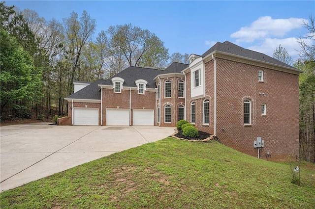 view of front of home featuring an attached garage, concrete driveway, a front lawn, and brick siding