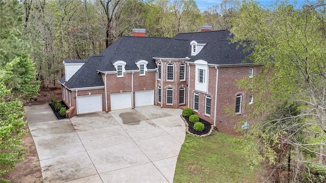 view of front of home with a chimney, driveway, a garage, and brick siding