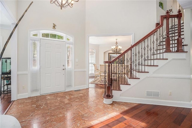 foyer entrance with a chandelier, stairway, visible vents, and hardwood / wood-style floors