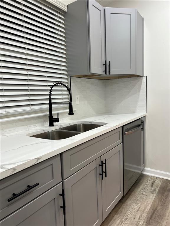 kitchen featuring gray cabinetry, sink, light hardwood / wood-style flooring, and stainless steel dishwasher