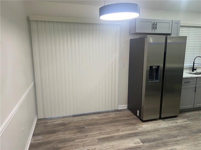 kitchen with stainless steel refrigerator with ice dispenser, sink, decorative light fixtures, gray cabinets, and hardwood / wood-style floors