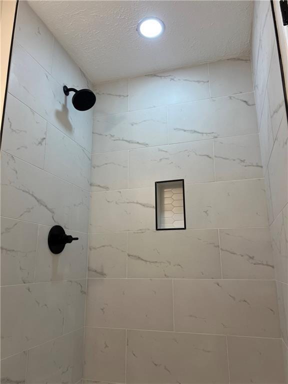 bathroom with tiled shower and a textured ceiling