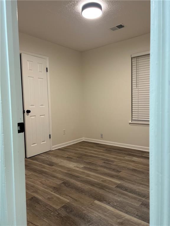 spare room featuring dark hardwood / wood-style floors and a textured ceiling