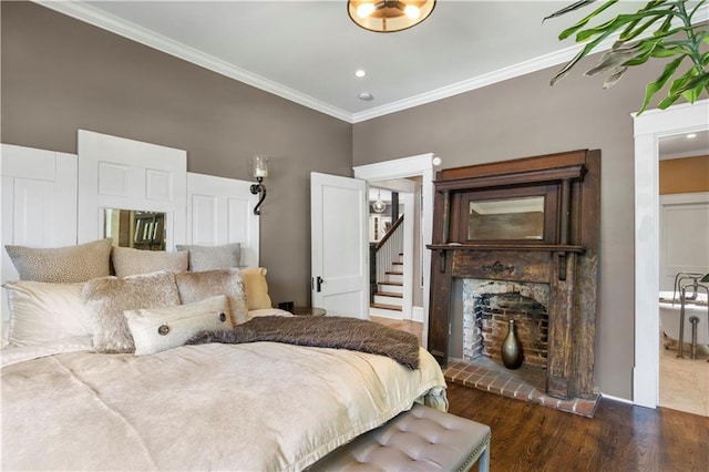 bedroom with crown molding, a fireplace, and wood finished floors