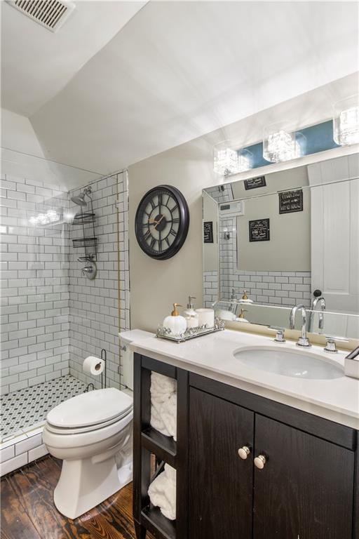 bathroom with visible vents, a shower stall, wood finished floors, vanity, and toilet