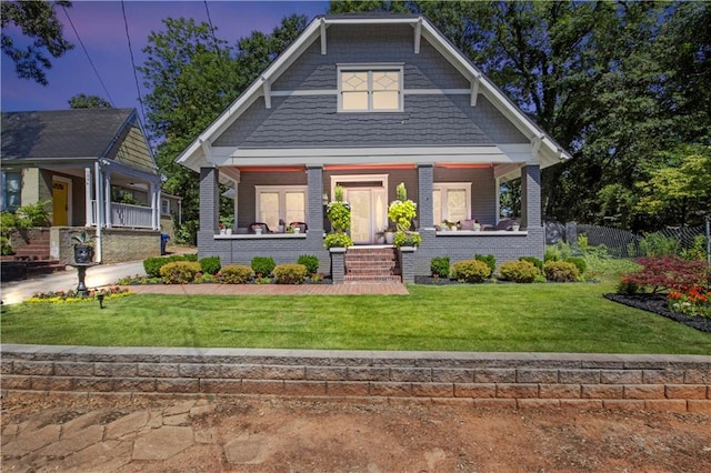 craftsman-style home with covered porch, a front yard, and brick siding