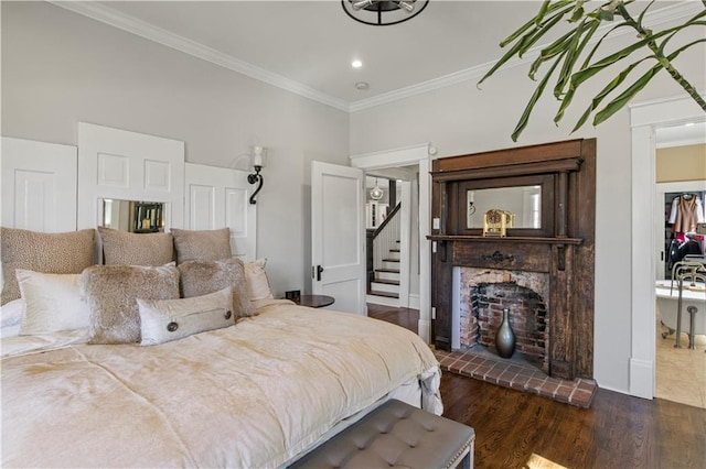 bedroom featuring crown molding, a brick fireplace, wood finished floors, baseboards, and recessed lighting