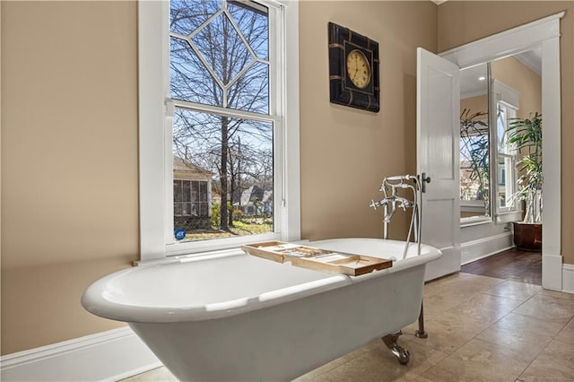 bathroom with baseboards, a freestanding bath, and a wealth of natural light
