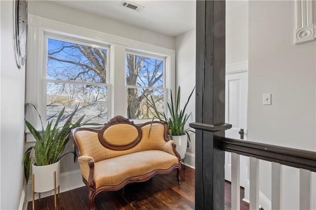 living area with baseboards, visible vents, and wood finished floors