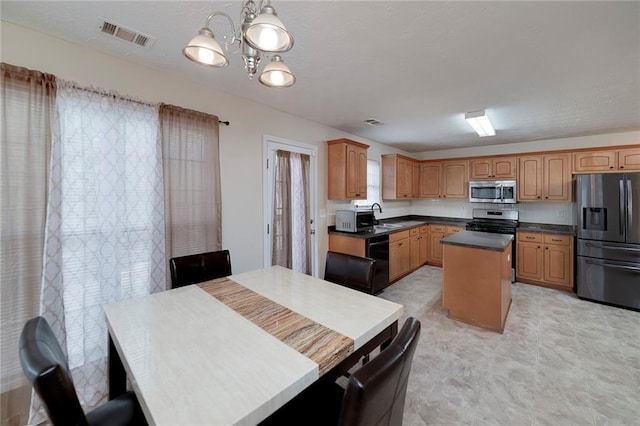 kitchen with sink, decorative light fixtures, appliances with stainless steel finishes, a kitchen island, and a notable chandelier