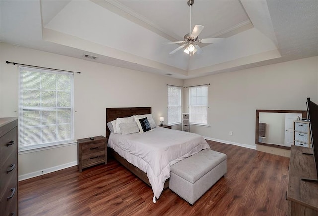 bedroom with multiple windows, dark hardwood / wood-style flooring, and a tray ceiling