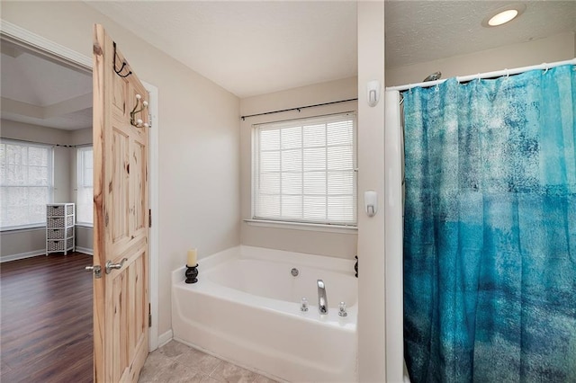 bathroom with wood-type flooring, a textured ceiling, and a washtub