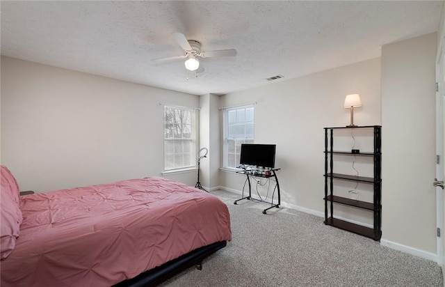 carpeted bedroom featuring ceiling fan and a textured ceiling