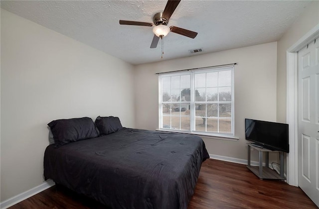 bedroom featuring ceiling fan, dark wood-type flooring, and a textured ceiling