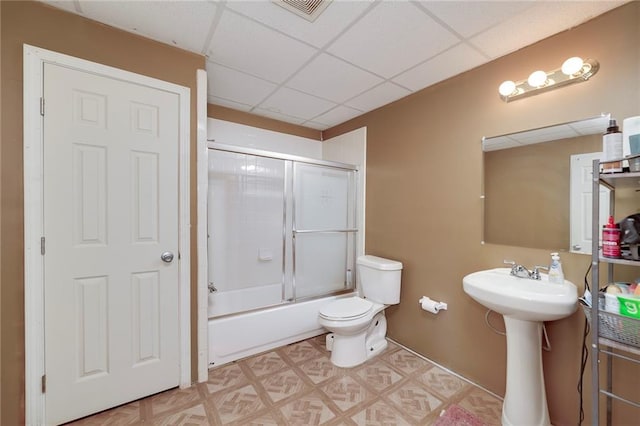 bathroom with combined bath / shower with glass door, a paneled ceiling, and toilet