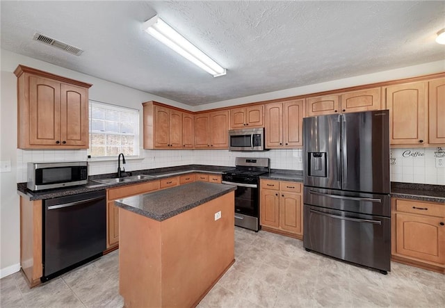 kitchen with a kitchen island, appliances with stainless steel finishes, sink, decorative backsplash, and a textured ceiling