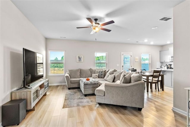 living room with a wealth of natural light, ceiling fan, and light hardwood / wood-style flooring