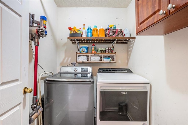 laundry room featuring separate washer and dryer, a textured ceiling, and cabinets