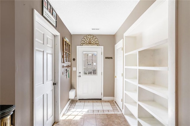 entryway with a textured ceiling and light tile patterned floors