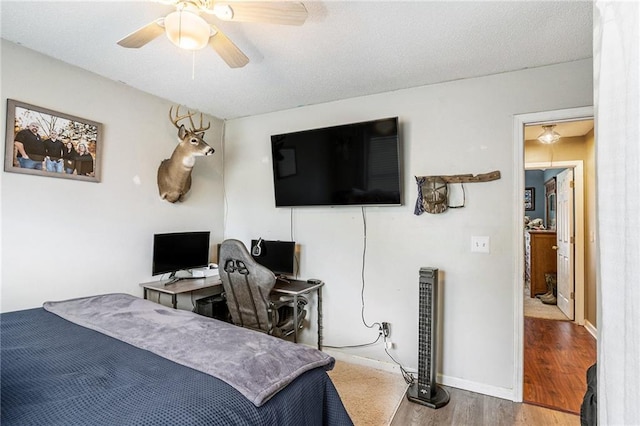 bedroom with a textured ceiling, wood-type flooring, and ceiling fan