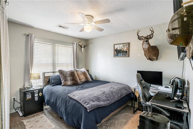 bedroom with a textured ceiling, hardwood / wood-style floors, and ceiling fan