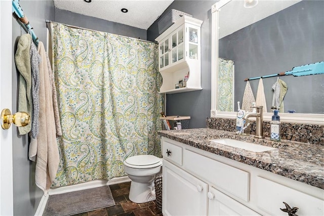 bathroom with a textured ceiling, vanity, toilet, and walk in shower