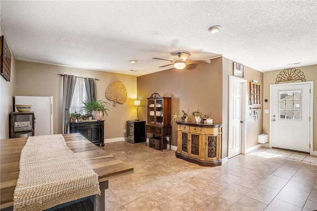 living room with a textured ceiling, ceiling fan, and tile patterned flooring