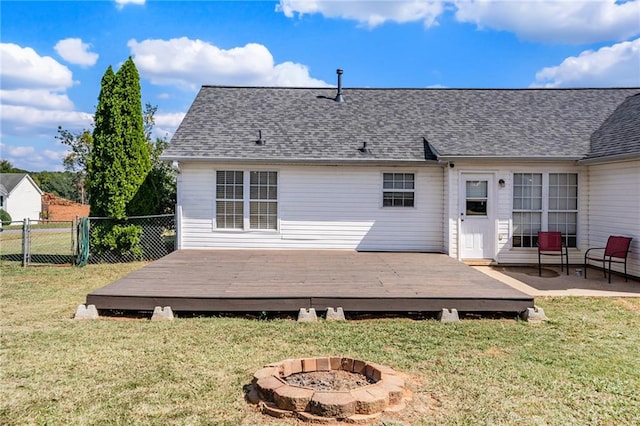 back of house with an outdoor fire pit, a deck, and a yard