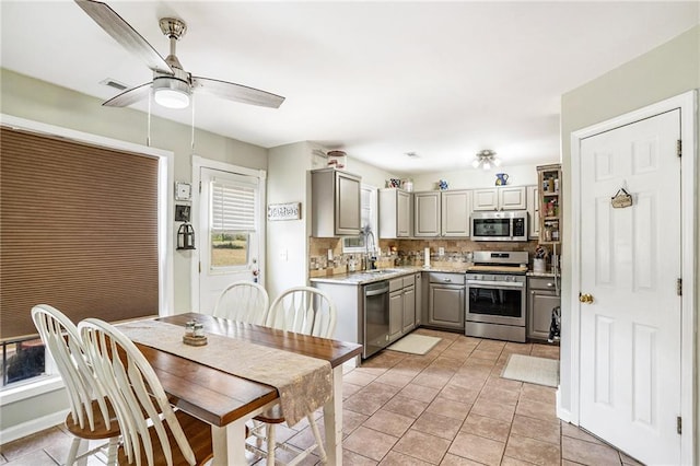 kitchen with appliances with stainless steel finishes, sink, gray cabinets, ceiling fan, and decorative backsplash