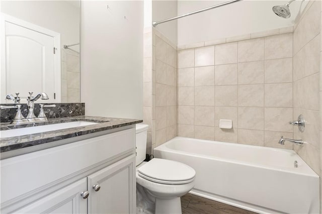 full bathroom featuring vanity, tiled shower / bath combo, toilet, and hardwood / wood-style flooring