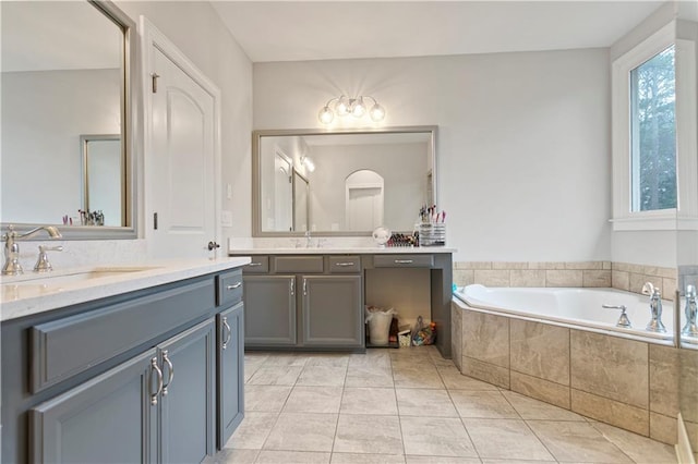 bathroom with tiled tub, double vanity, and tile floors