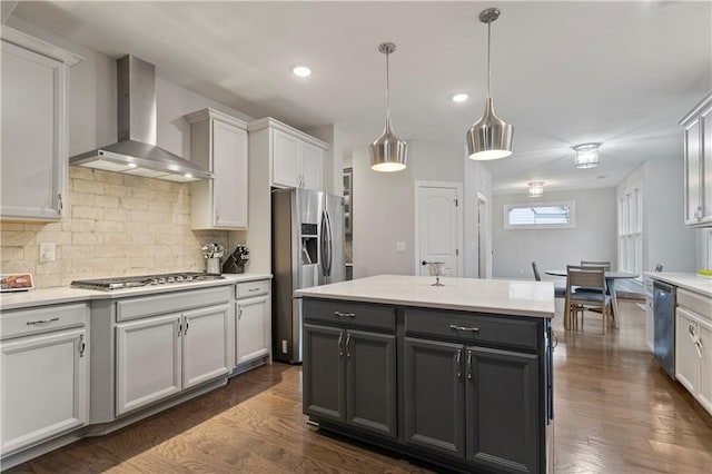 kitchen with wall chimney range hood, hanging light fixtures, backsplash, and dark wood-type flooring